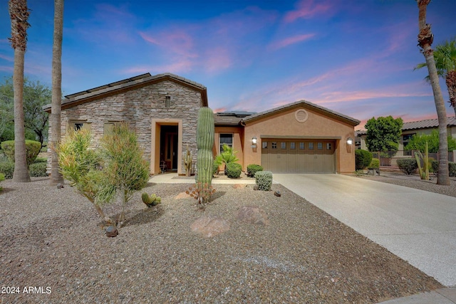 view of front facade with a garage, stone siding, concrete driveway, roof mounted solar panels, and stucco siding