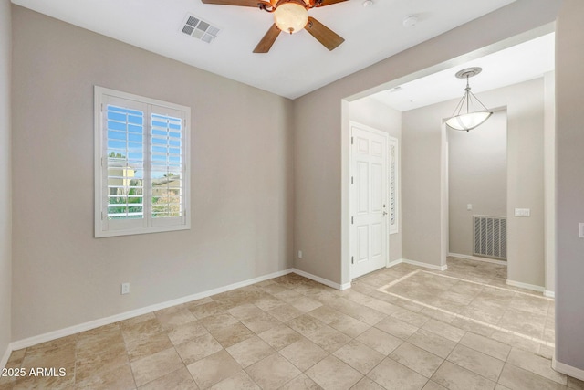 spare room featuring baseboards, visible vents, and a ceiling fan