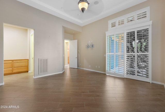 spare room with baseboards, visible vents, and wood finished floors