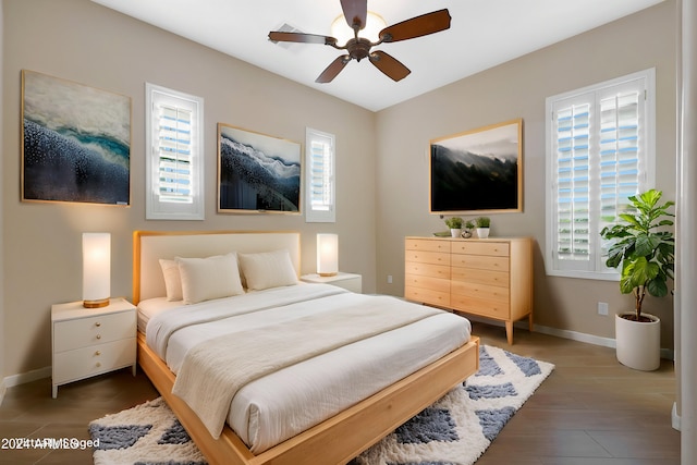 bedroom featuring a ceiling fan, multiple windows, baseboards, and wood finished floors