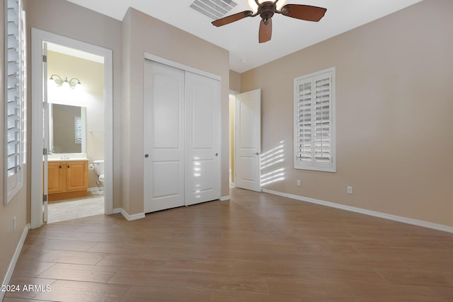 unfurnished bedroom featuring a closet, visible vents, ensuite bathroom, wood finished floors, and baseboards