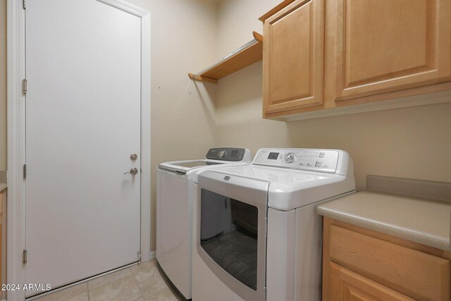 clothes washing area with light tile patterned floors, washing machine and dryer, and cabinet space