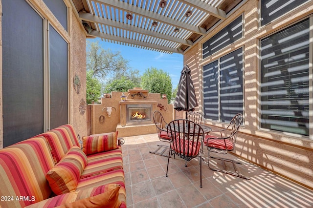 view of patio / terrace featuring outdoor dining space, a lit fireplace, and a pergola