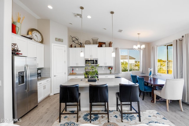 kitchen with decorative backsplash, stainless steel appliances, white cabinets, a kitchen island, and lofted ceiling