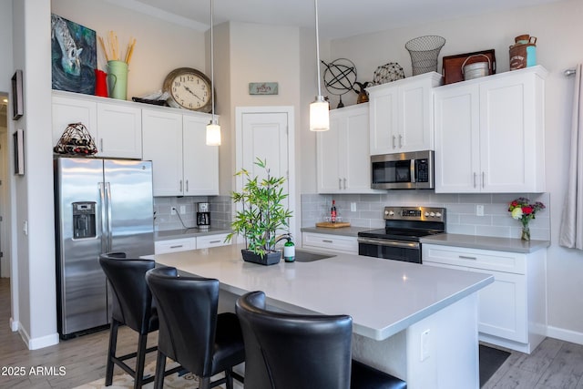 kitchen featuring decorative light fixtures, decorative backsplash, stainless steel appliances, and an island with sink