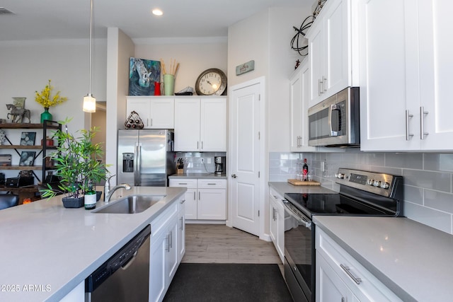 kitchen with backsplash, stainless steel appliances, sink, white cabinetry, and hanging light fixtures