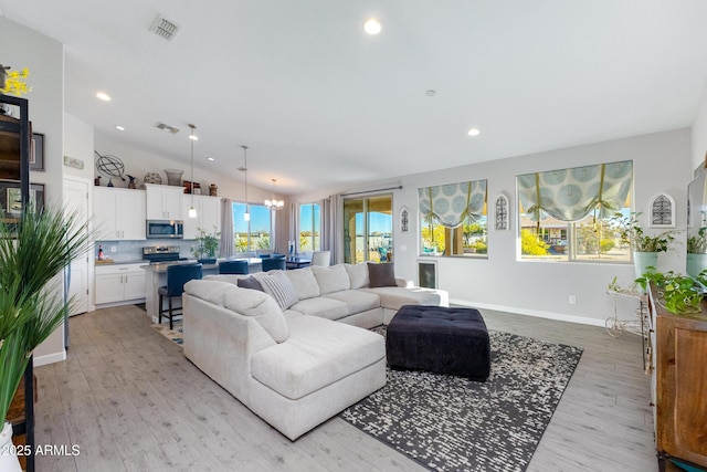 living room featuring light wood-type flooring, lofted ceiling, and a notable chandelier