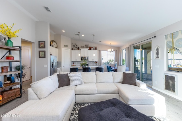 living room with light hardwood / wood-style floors, lofted ceiling, and a notable chandelier