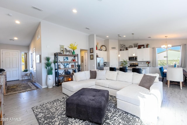 living room with light hardwood / wood-style floors and a notable chandelier