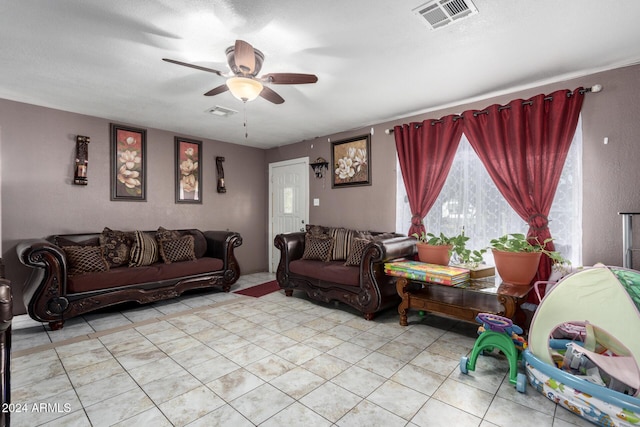 living room with ceiling fan, light tile patterned floors, and a textured ceiling