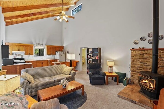 living room with a wood stove, light carpet, high vaulted ceiling, ceiling fan, and beam ceiling