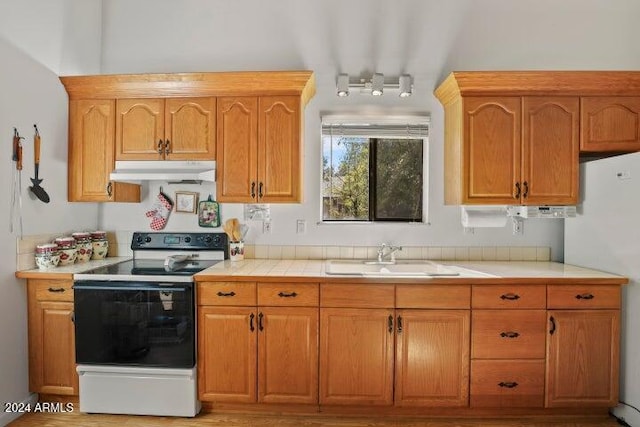 kitchen with tile counters, light wood-type flooring, white appliances, and sink