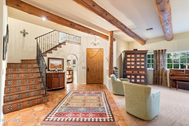 entryway featuring carpet flooring, a notable chandelier, and beam ceiling