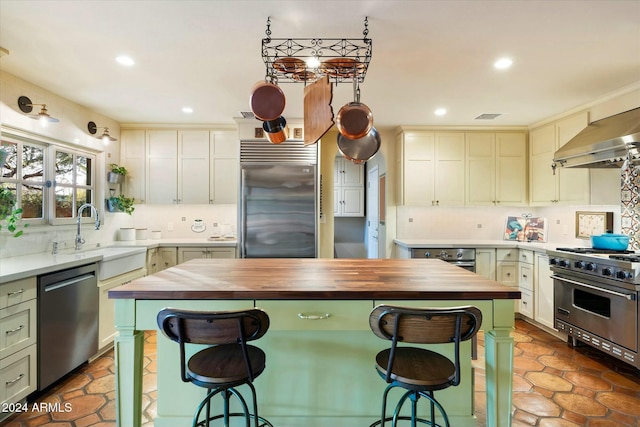 kitchen with backsplash, premium appliances, sink, a center island, and butcher block countertops