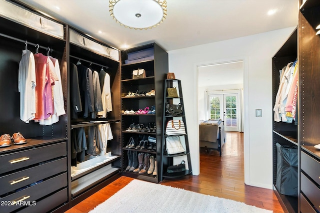 walk in closet with french doors and dark hardwood / wood-style flooring