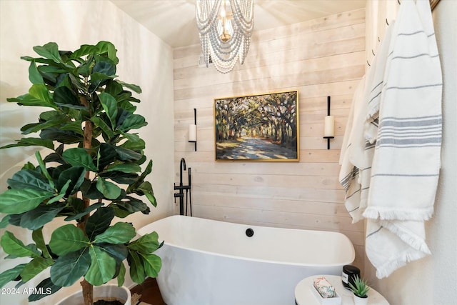 bathroom with wooden walls, a bathtub, and an inviting chandelier