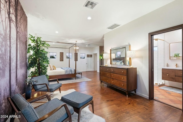 bedroom featuring hardwood / wood-style flooring, ensuite bathroom, and a chandelier