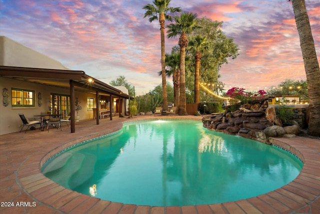 pool at dusk with a patio area