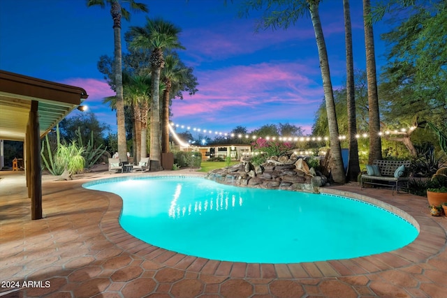 pool at dusk with a patio area