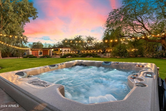 pool at dusk featuring a yard and a hot tub