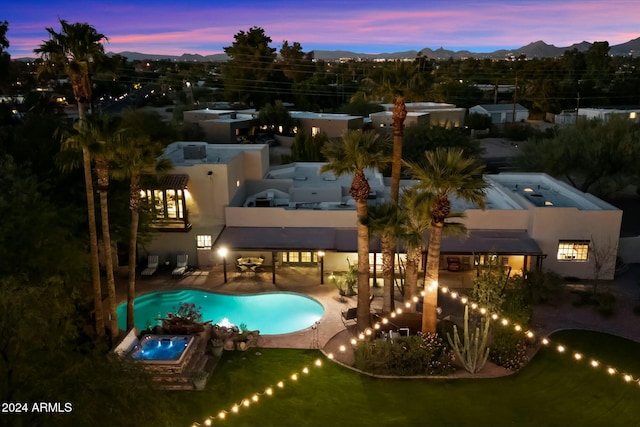 pool at dusk with an in ground hot tub and a patio