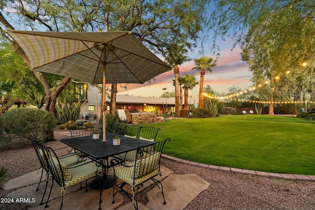 patio terrace at dusk featuring a lawn