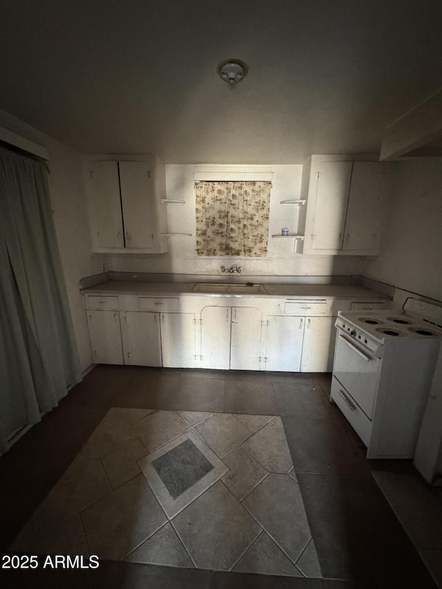 kitchen featuring dark tile patterned floors, white cabinetry, sink, and white range with electric stovetop