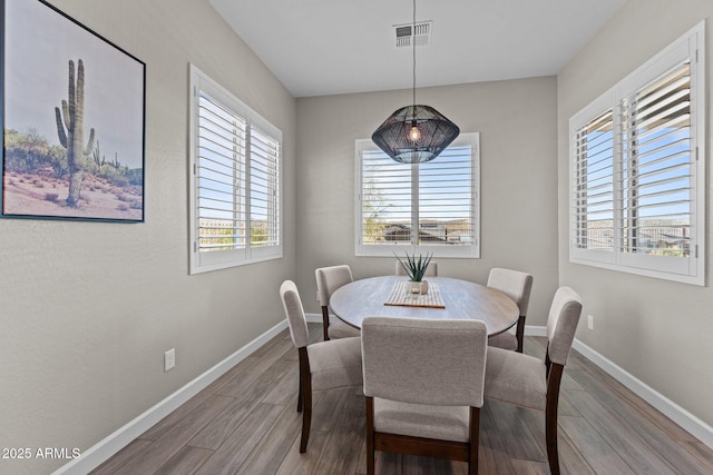 dining area featuring visible vents, baseboards, and wood finished floors