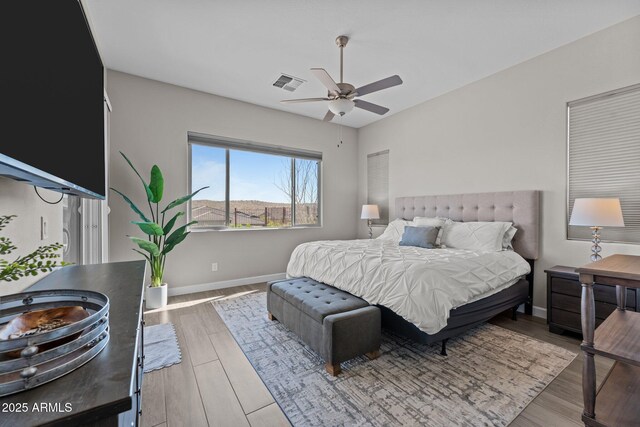 bedroom with baseboards, visible vents, ceiling fan, and wood finished floors