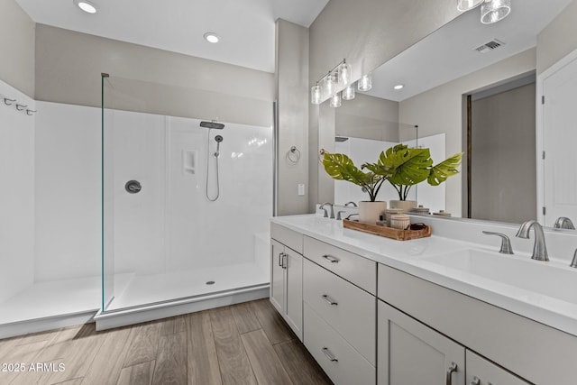 bathroom featuring a walk in shower, visible vents, a sink, and wood finished floors