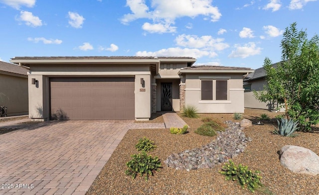 prairie-style house with a garage, decorative driveway, and stucco siding