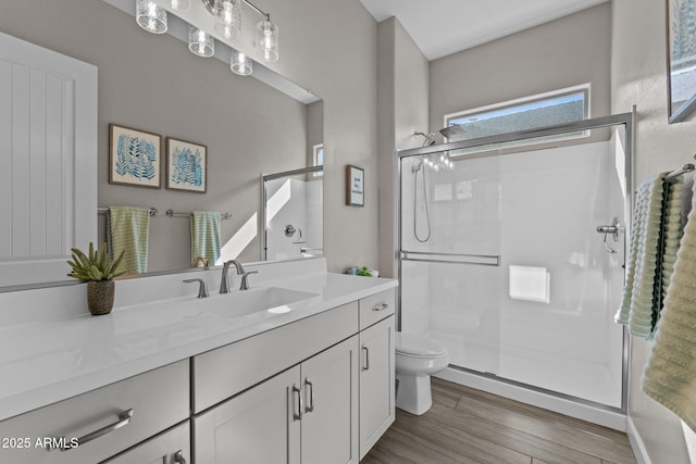 bathroom featuring vanity, a shower stall, toilet, and wood finished floors