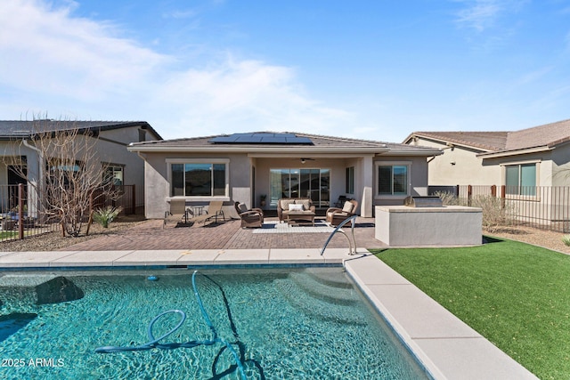 back of property with a fenced backyard, an outdoor hangout area, solar panels, stucco siding, and a patio area