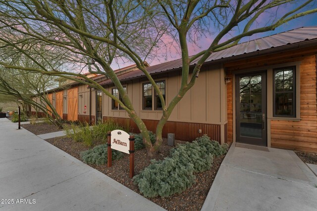 exterior entry at dusk featuring metal roof and board and batten siding