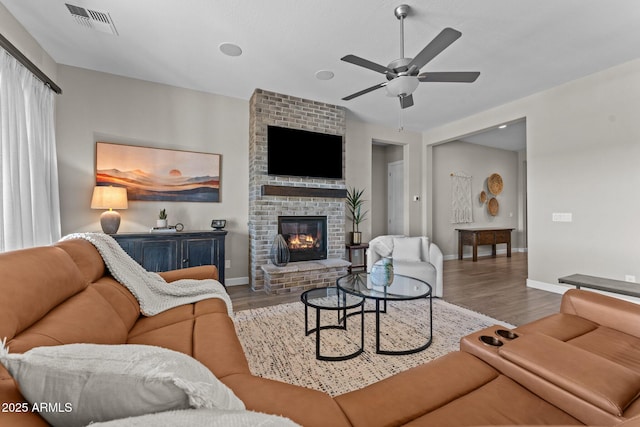 living area featuring visible vents, a fireplace, baseboards, and wood finished floors