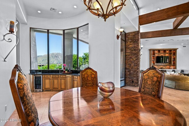 dining space with a high ceiling, wine cooler, a notable chandelier, a mountain view, and bar