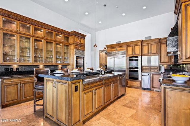 kitchen with sink, stainless steel appliances, an island with sink, decorative light fixtures, and a breakfast bar area