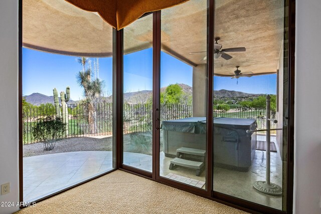 doorway with a mountain view, carpet floors, and ceiling fan