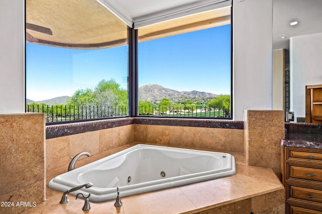 bathroom with a relaxing tiled tub, a mountain view, and a healthy amount of sunlight