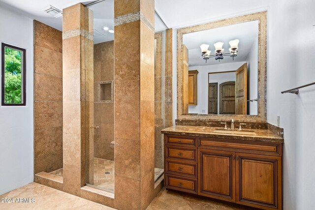 bathroom featuring tiled shower, vanity, and a chandelier