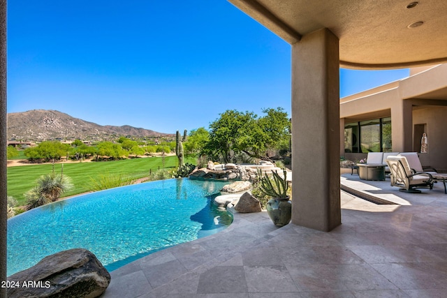 view of pool featuring a mountain view, a patio area, and a lawn