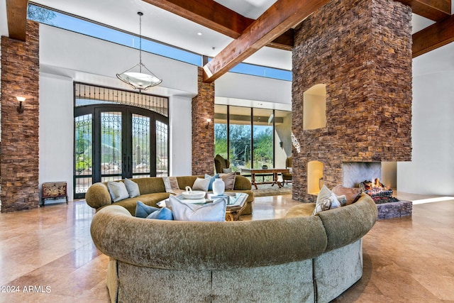 living room featuring beam ceiling, a fireplace, a towering ceiling, and french doors