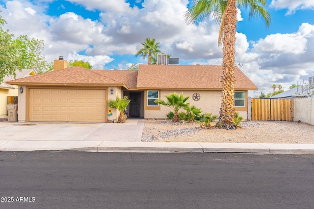 ranch-style home with a gate, fence, driveway, an attached garage, and stucco siding