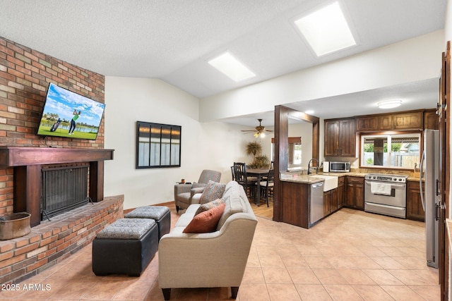 living room featuring ceiling fan, lofted ceiling, light tile patterned floors, a fireplace, and a textured ceiling