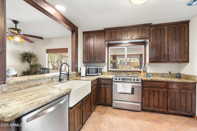 kitchen featuring light stone counters, stainless steel appliances, a peninsula, and light tile patterned floors