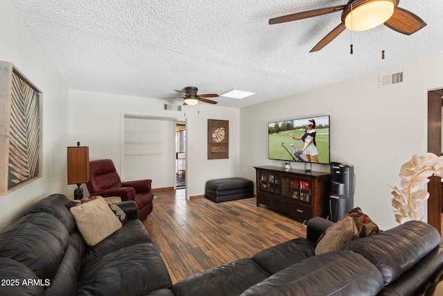 living area with visible vents, a textured ceiling, wood finished floors, and a ceiling fan