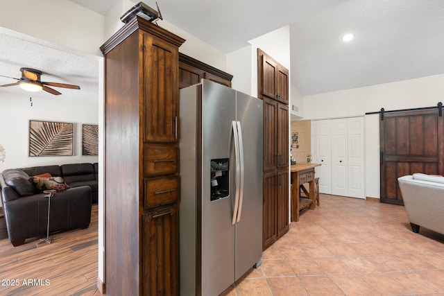 kitchen featuring stainless steel fridge with ice dispenser, open floor plan, lofted ceiling, a barn door, and a ceiling fan