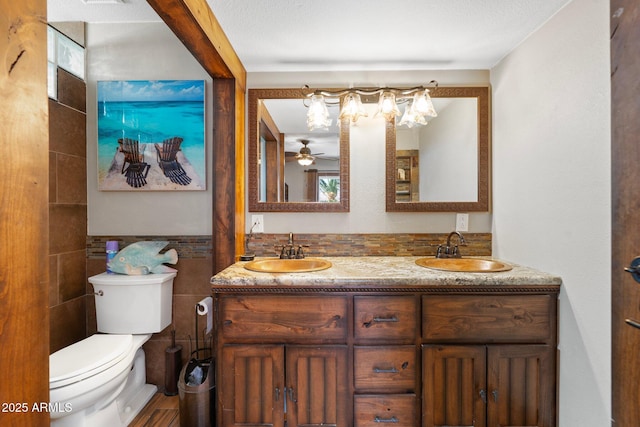 bathroom featuring a sink, toilet, tile walls, and double vanity