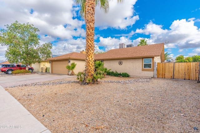 view of front of house with an attached garage, fence, stucco siding, driveway, and a gate