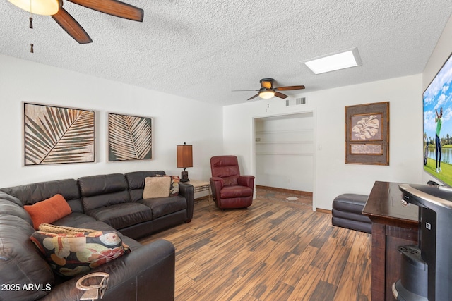 living area featuring visible vents, baseboards, wood finished floors, a textured ceiling, and a ceiling fan